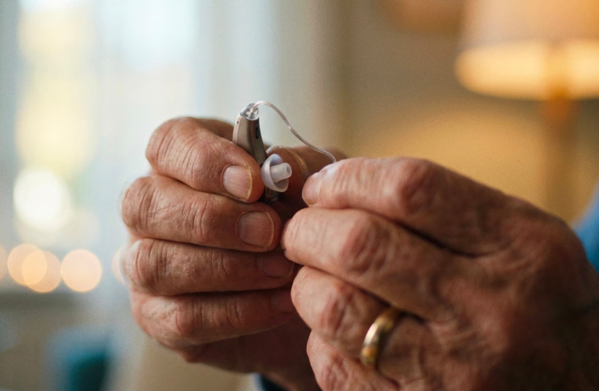 Hands changing a dome on a hearing aid